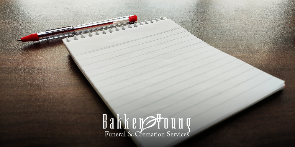 Phone, notepad, and pen on a table, symbolizing first calls and steps when a death occurs