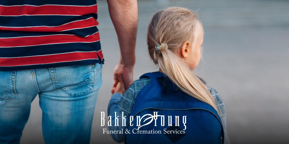 Parent walking a child to school with backpacks, viewed from behind, symbolizing grief at the start of the school year